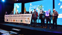 Des hommes et femmes portent une banderole sur un podium