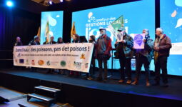 Des hommes et femmes portent une banderole sur un podium