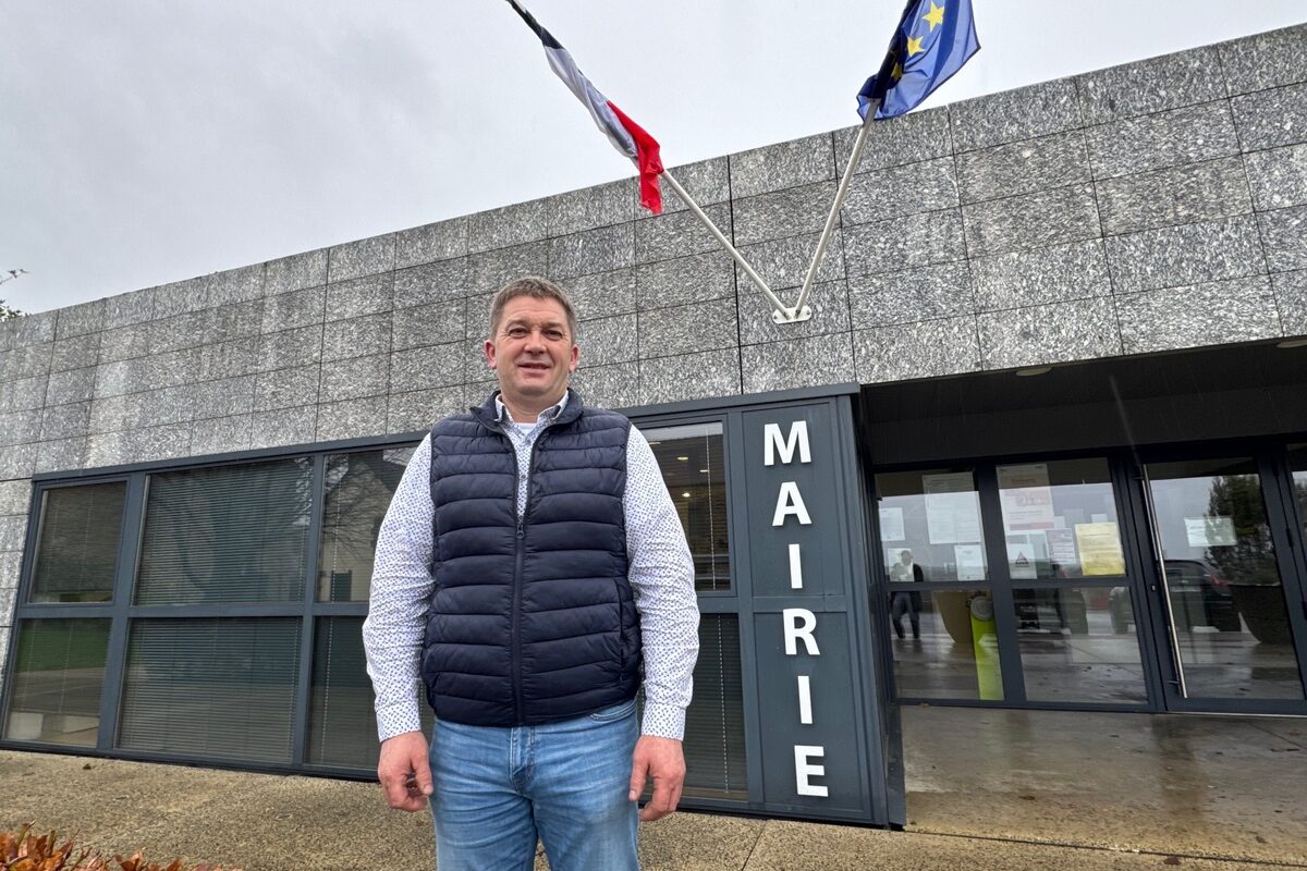 Un homme devant une mairie présentant les drapeaux de la France et de l'Europe.  - Illustration Faire entendre les agriculteurs