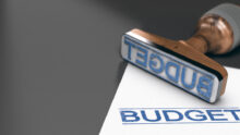 Une feuille et un tampon à encre "Budget" sur une table. Le tampon bleu a été aposé sur la feuille.