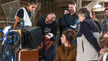 Un tournage de film dans une ferme avec des hommes et des femmes qui regardent la scène sur un écran