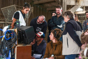 Un tournage de film dans une ferme avec des hommes et des femmes qui regardent la scène sur un écran