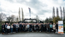 Un groupe de personnes devant 2 tracteurs avec des godets qui forment une arche