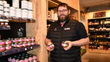 un homme tient des boîtes de pâté devant des étagères