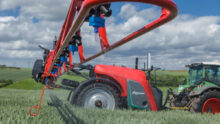 Vue de profil d'un pulvérisateur agricole et d'un tracteur au travail au champ