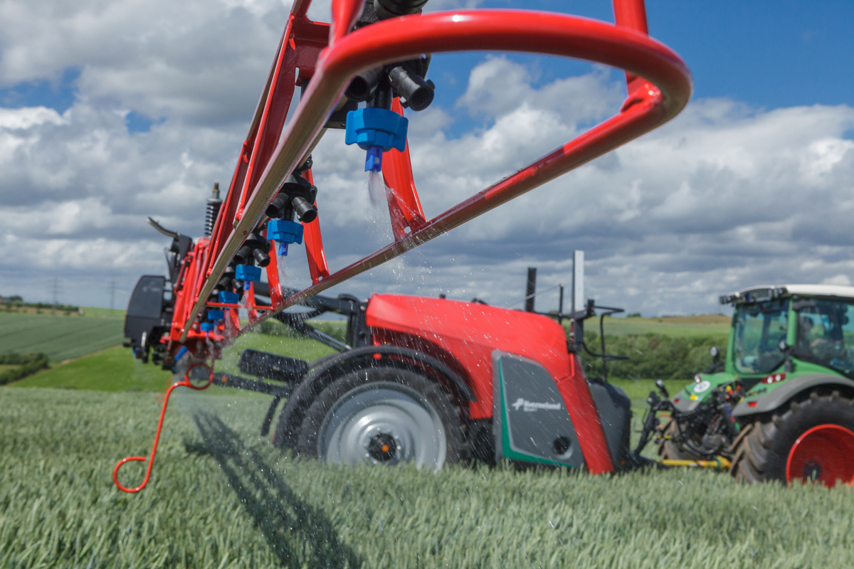 Vue de profil d'un pulvérisateur agricole et d'un tracteur au travail au champ - Illustration Adapter la buse anti-dérive et le volume de bouillie selon le produit