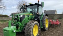 Un tracteur au travail avec une masse à l'avant et une charrue attelée