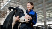 shutUne jeune femme qui caresse la tête d'une vache en la regardant tendrement