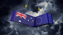 Infographie de 2 containers, un avec le drapeau australien et l'autre avec le drapeau européen. Ils sont suspendus et se cognent dans un ciel d'orage