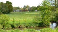 Un paysage de campagne verdoyant traversé au premier plan par une rivière