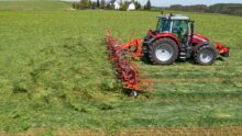 Un tracteur avec une faneuse attelée au champ