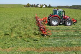 Un tracteur avec une faneuse attelée au champ
