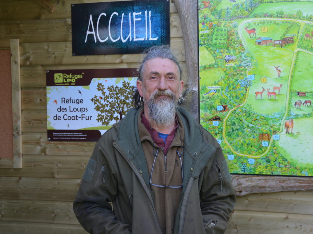 Un homme devant l'accueil d'un refuge pour loups