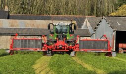 Un tracteur équipé d'un groupe de fauche coupe de l'herbe dans une prairie