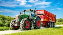 Un tracteur avec une remoque sur une petite route