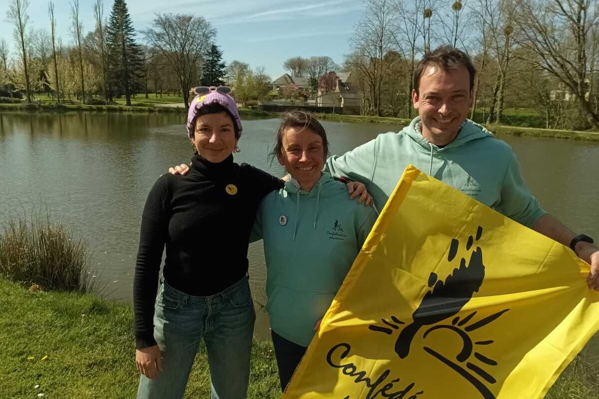 un homme et deux femmes au bord d'une rivière avec un drapeau de la Confédération Paysanne - Illustration De nouveaux porte-paroles à la Conf  du Morbihan