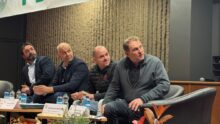 Quatre homme assis autour d'une table regardent sur leur gauche