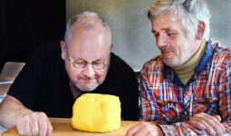 Deux hommes observent et sentent une motte de beurre artisanale posée sur une planche