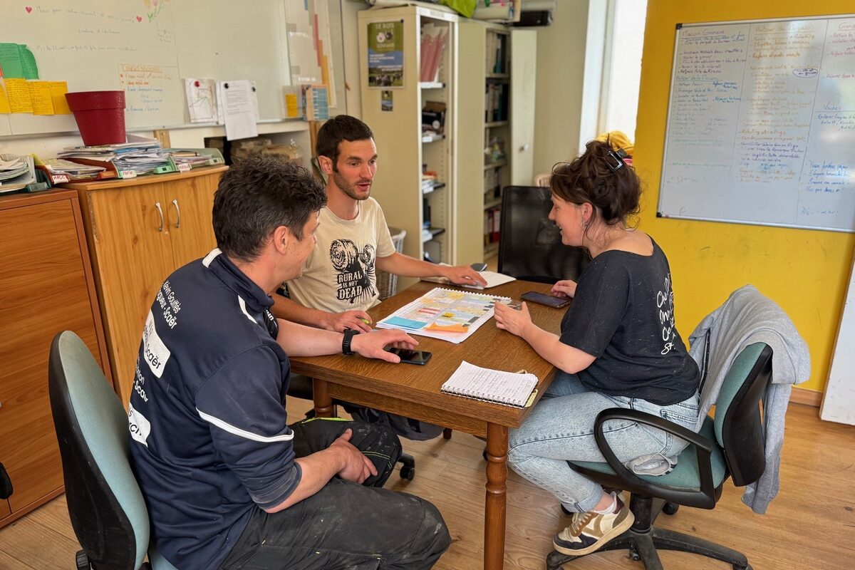 Deux hommes et une femme en réunion autour d'une table - Illustration Bien organisés pour fonctionner en collectif