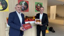 2 personnes dans un hall tenant des fraises et des tomates devant un étal de légumes