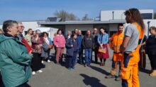 Des personnes regroupées sur un parking en train d'écouter une autre qui parle