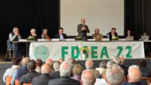 Huit personnes à la tribune d'une assemblée générale devant un public de séniors