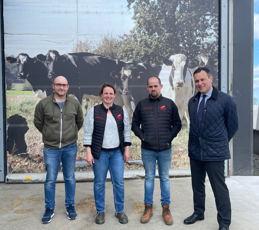 Trois hommes et une femme devant un poster de vaches laitières - Illustration Les nouveaux responsables de JA accueillent le préfet à la ferme