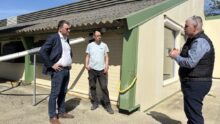 Des personnes devant un bâtiment d'élevage de volailles