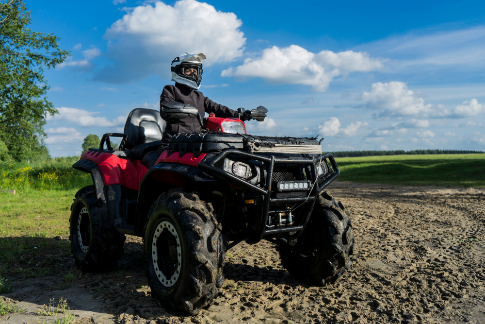 Une personne équipée (casque, gants, veste..) sur un quad dans un champ - Illustration Conduite de Quad : prévenir l’accident avant qu’il ne survienne