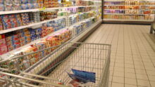 Un caddie dans une allée de supermarché au rayon yaourt