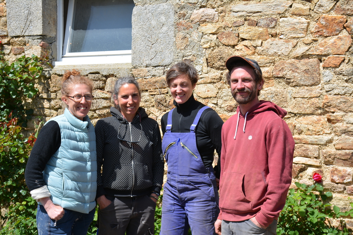 Trois femmes et un homme posent devant une maison en pierre - Illustration Paysans et artisans s’entraident au sein d’un collectif