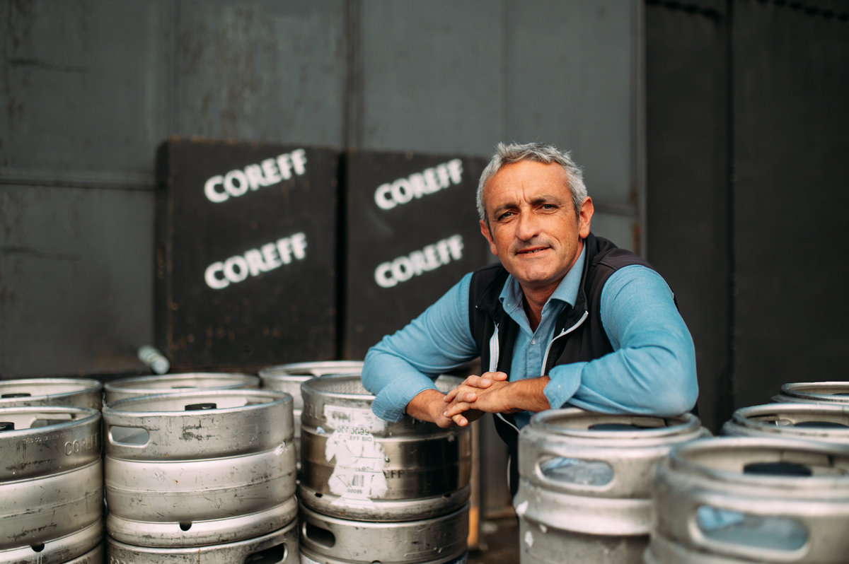 Un homme pose au milieu de fûts de bière Coreff - Illustration Brasseur d’idées